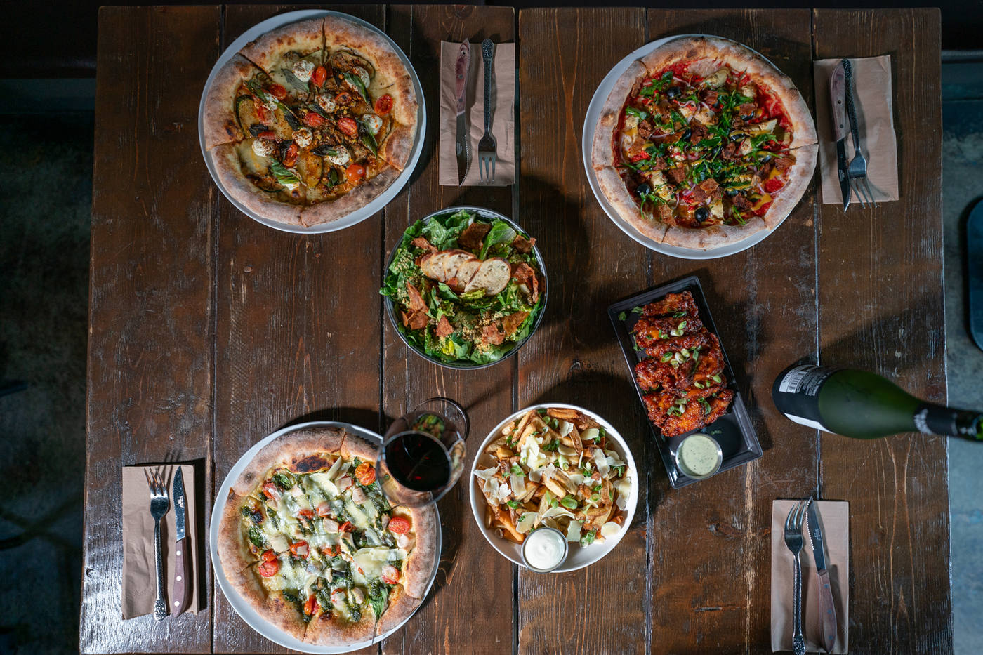 Wood-fired pizzas, salads and wings on a wooden table